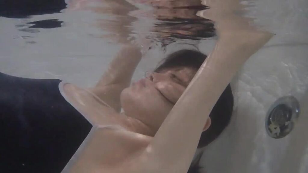 水中で腕を上げたまま、仰向けで沈むゲストモデルDさん
