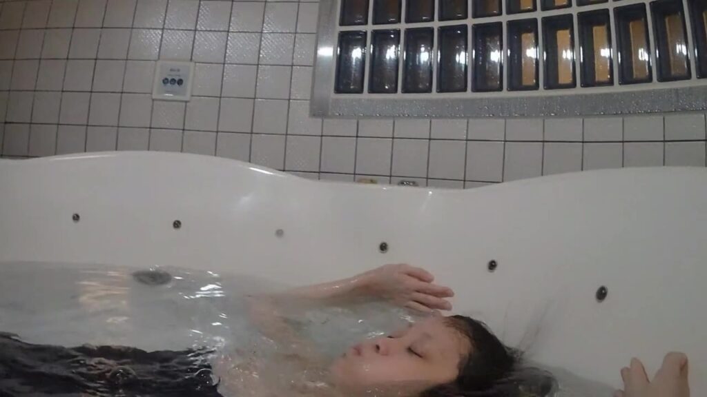 浴槽で仰向けになり、顔を水面に沈めていくゲストモデルDさん