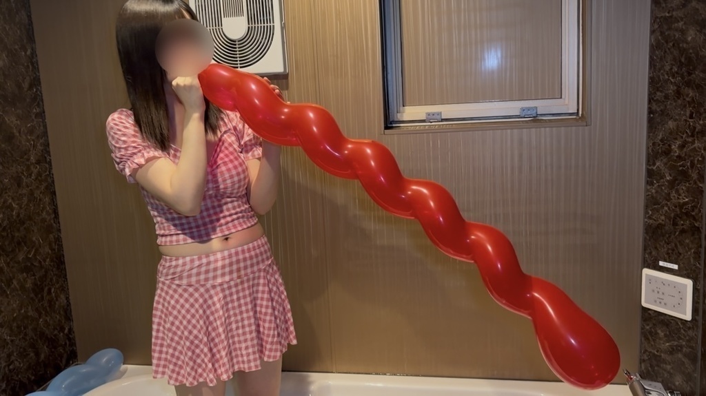 赤色の風船を膨らませる水着姿の女の子