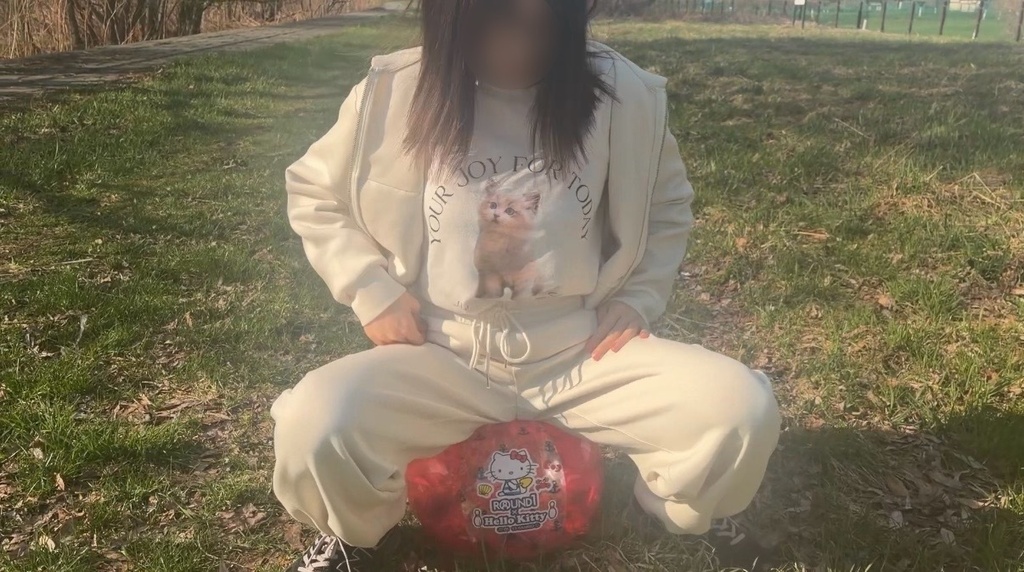 空ビフェチの白い服を着た女の子がビーチボールの上に座ってる正面から撮影した写真