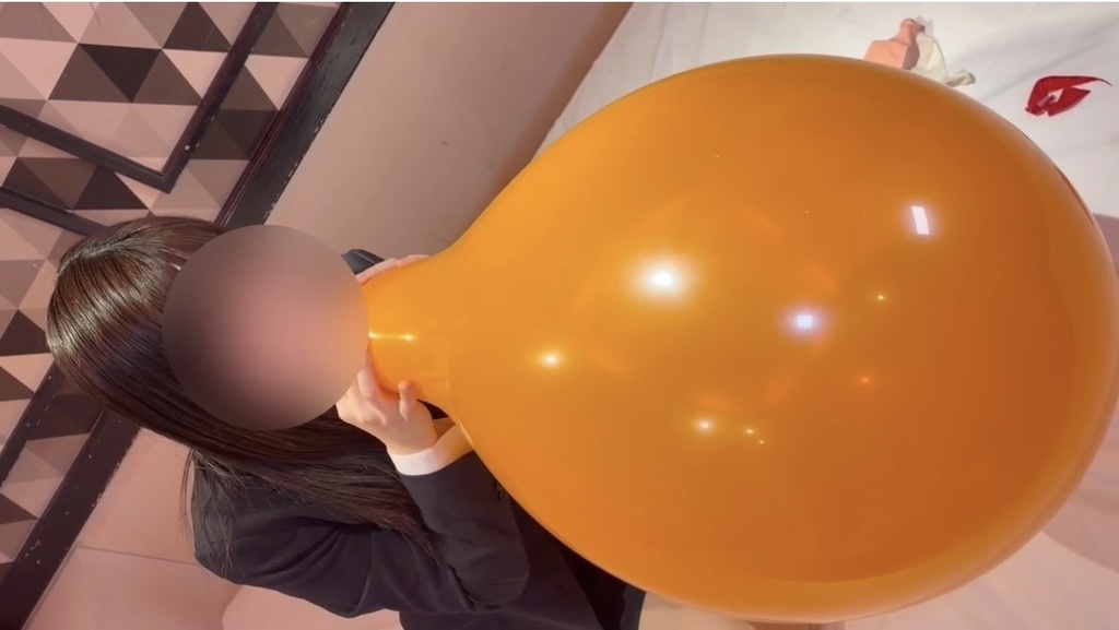 大きな風船を口で膨らましてる女の子