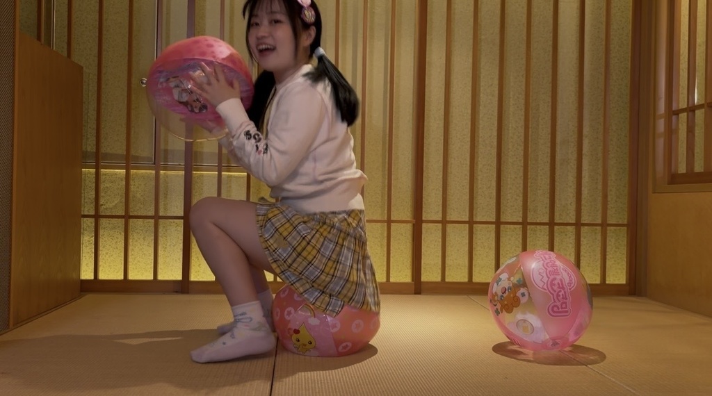 ビーチボールの上に座ってバウンドする女の子